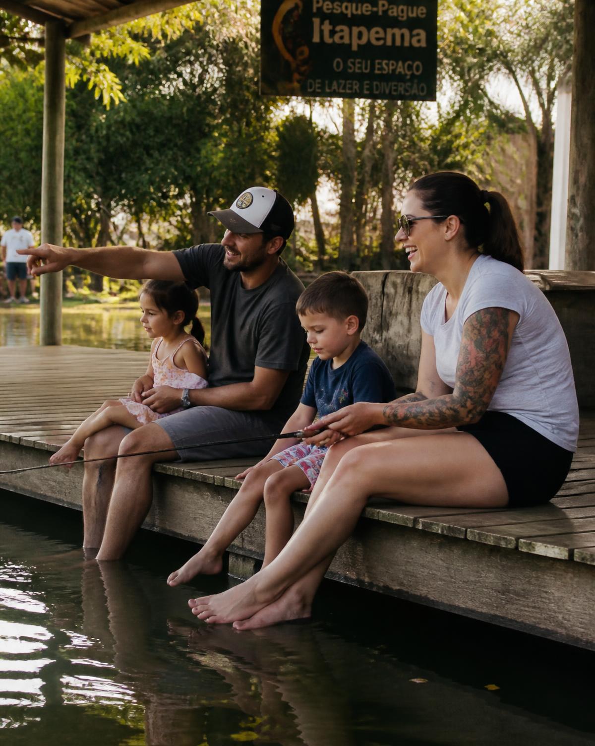 Família sentada no deque de madeira pescando à tarde